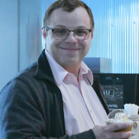 Smiling man in glasses holds drink, exuding warmth and hospitality, at Lakeview Christian Church in Portage Lakes